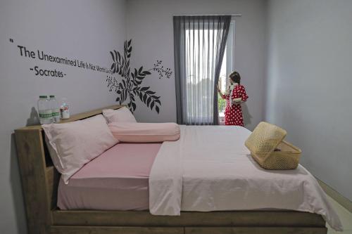 a woman standing in a bedroom looking out the window at Villa Palm Springs by REQhome in Ciater-hilir