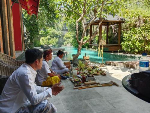 a group of people sitting around a table by a pool at Melo Suites Hotel in Seminyak