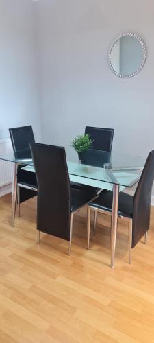 a glass dining table with black chairs and a potted plant at JB LUXURY APARTMENT in London