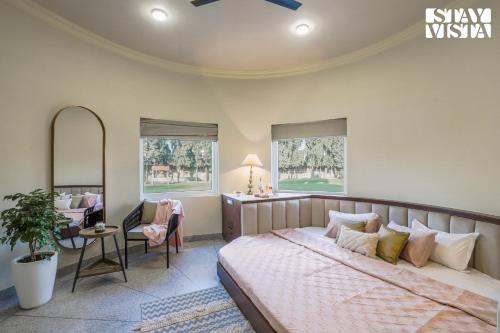 a bedroom with a bed and a chair and windows at StayVista's Mystic Castle with Terrace, Swimming Pool, Lawn with Gazebo in Jaipur