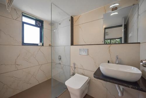 een badkamer met een wastafel, een toilet en een spiegel bij Bellezza By Stayscape Villas in Kārli