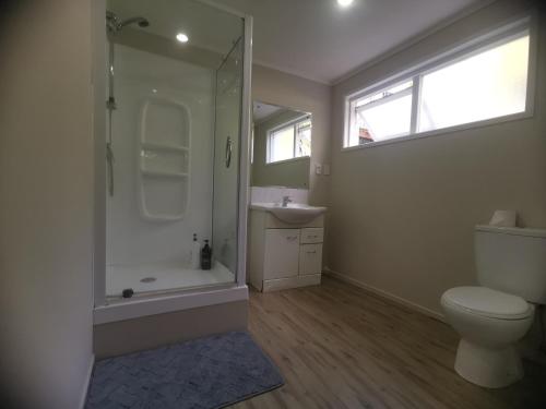 uma casa de banho com um chuveiro, um WC e um lavatório. em Sunshine hillcrest home em Auckland