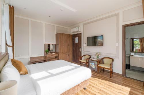 a bedroom with a white bed and a table and chairs at PINE VIEW Hotel Dalat in Da Lat