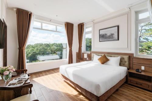 een slaapkamer met een wit bed en een groot raam bij PINE VIEW Hotel Dalat in Da Lat