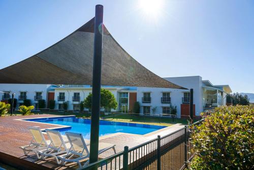 a swimming pool with two chairs and a large umbrella at Springs Shoalhaven Nowra in Nowra