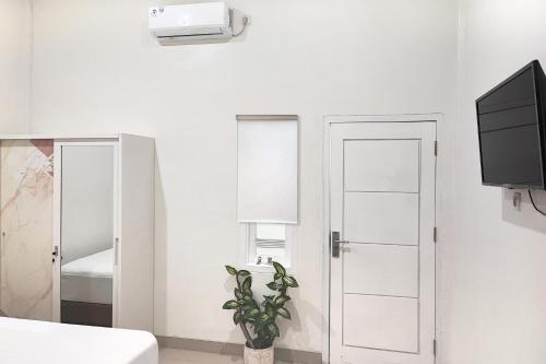 une chambre blanche avec une télévision et une plante dans l'établissement Urbanview Hotel Syariah near Polda Jambi, à Palmerah