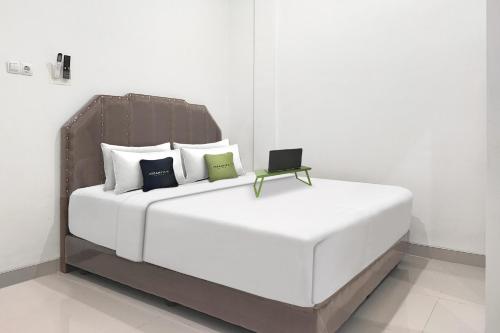 a large white bed with a laptop sitting on it at Urbanview Hotel Syariah near Polda Jambi in Paalmerah