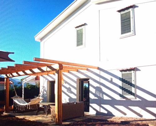 a white house with a wooden pergola next to it at LE SORELLE entire villa sea view in Scopello