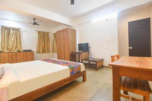 una camera da letto con un letto, una scrivania e una televisione di FabExpress Holiday Suites - Nr Benaulim Beach a Benaulim