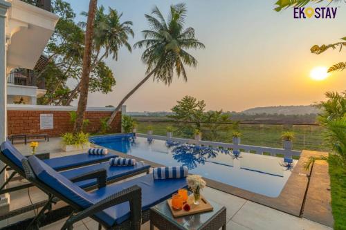 a villa with a swimming pool at sunset at EKOSTAY Luxe - Jade Villa I Infinity Pool I Paddy Field Views in Candolim