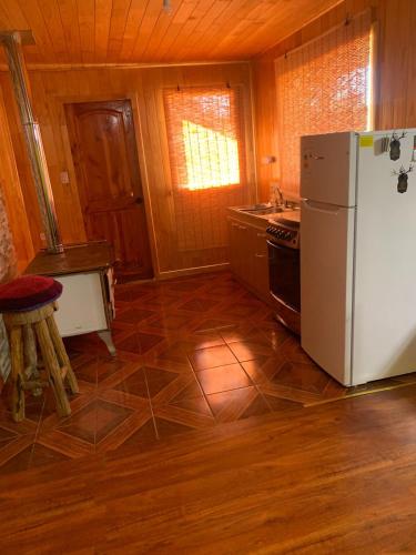 uma cozinha com um frigorífico branco e um fogão em Butamacho Cabaña con Tinaja x Día em Chonchi