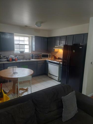 a kitchen with a black refrigerator and a table at Cosy Bedroom 12mins to Airport Prudential NJIT UMDJ Penn Station in Newark
