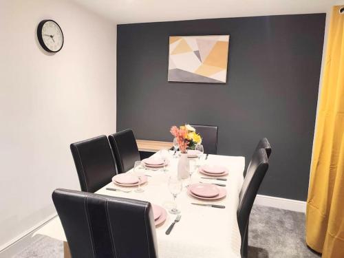 a dining room with a table with chairs and a clock at Sigma Lux Home in Cramlington