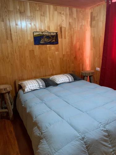 Cama grande en habitación con paredes de madera en Butamacho Cabaña con Tinaja x Día, en Chonchi