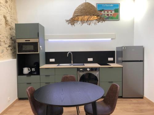 La cuisine est équipée d'une table, d'un évier et d'un réfrigérateur. dans l'établissement La Charmille - Côté Cour, à La Copechagnière