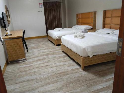 a bedroom with two beds and a desk with a television at Meaco Royal Hotel - Valenzuela in Subusub