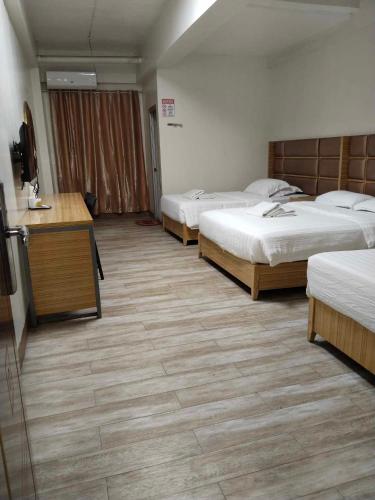 a hotel room with three beds and a desk at Meaco Royal Hotel - Valenzuela in Subusub