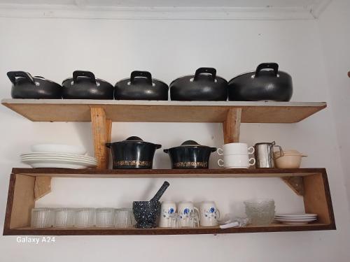 ein Regal mit Töpfen, Pfannen und Geschirr darauf in der Unterkunft Hideout in Ukunda