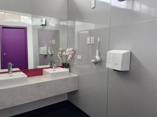 een badkamer met 2 wastafels en een paarse deur bij YHA Nelson in Nelson