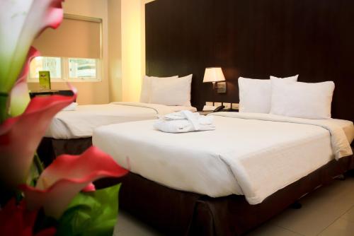 two beds in a hotel room with towels on them at CityState Tower Hotel in Manila