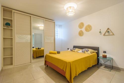 - une chambre avec un lit doté d'un couvre-lit jaune dans l'établissement Mélo Appart avec sa terrasse spacieuse et vue entre Mer & montagne, à Sainte-Marie