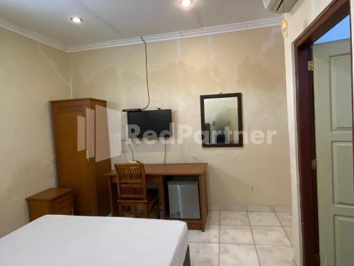 a room with a bed and a desk and a mirror at Hotel Kurnia @ Jln Pemuda Blora RedPartner in Blora