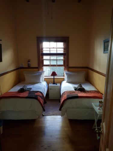 two beds in a room with a window at Uniondale Guest Lodge in Uniondale