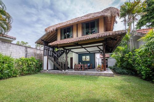 a house with a patio and a grass yard at Villa Coco Bali in Seminyak