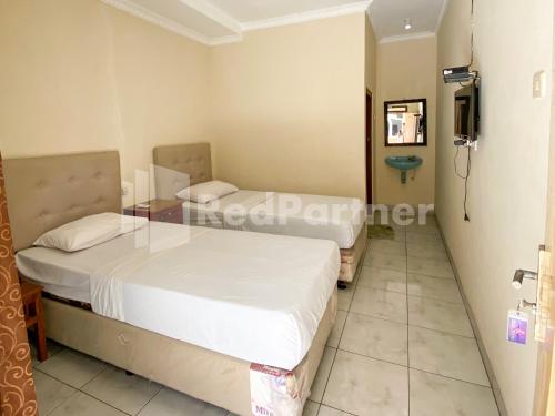 a bedroom with two beds and a tv in it at Hotel Kurnia @ Jln Pemuda Blora RedPartner in Blora