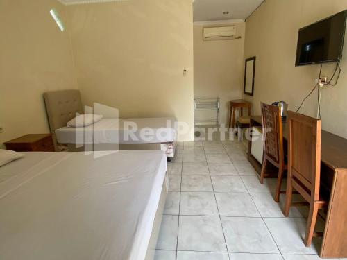 a room with a bed and a tv on the wall at Hotel Kurnia @ Jln Pemuda Blora RedPartner in Blora