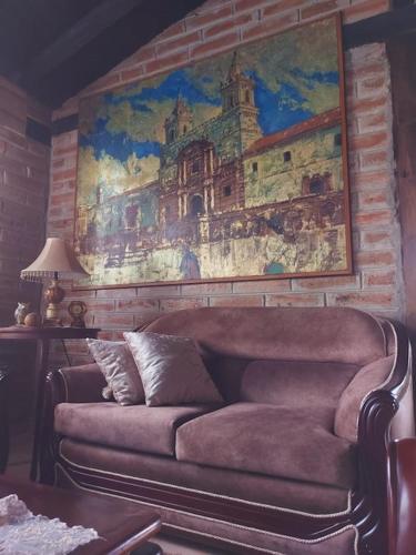 a couch in a living room with a painting on the wall at Quinta María Alfonsina in Ibarra