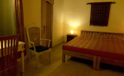 a bedroom with a bed and a chair and a lamp at Carik Tangis Boutique Homestay in Jatiluwih
