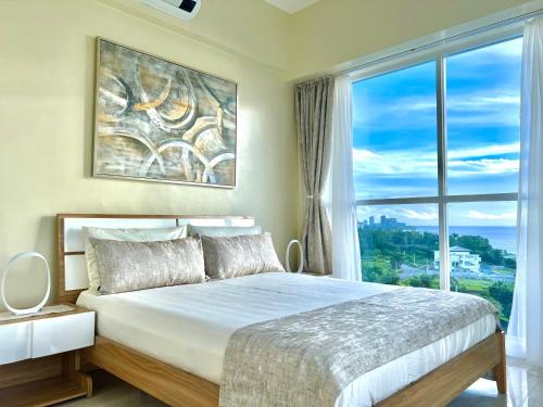 a bedroom with a large bed with a large window at Relaxing 1BR Suite in La Mirada in Mactan