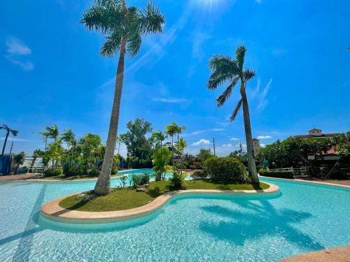 a swimming pool with palm trees in a resort at Relaxing 1BR Suite in La Mirada in Mactan