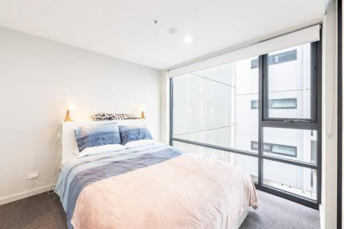 a bedroom with a bed and a large window at Convenient Located 2 bedroom apartment in Braddon in Canberra