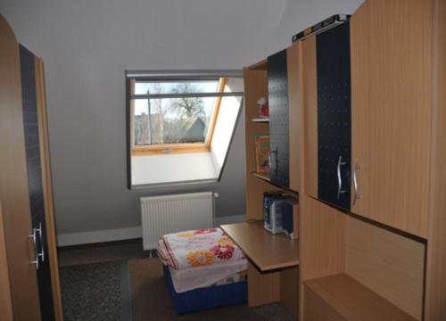 Neuendorf HeideにあるFerienhaus An der Heideのデスクと窓が備わる小さな客室です。