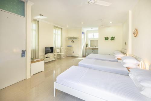 a hospital room with three beds and a television at Three Hearts in Fulhadhoo