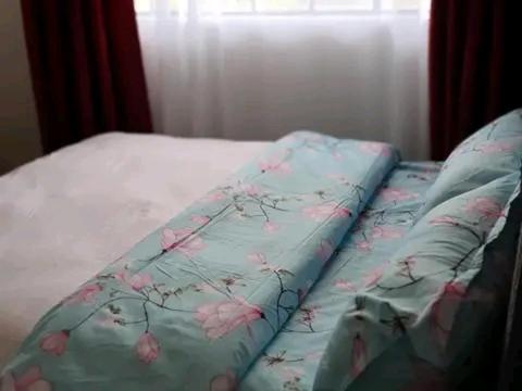 a bed with a blue blanket with pink flowers on it at Safaris hotels in Nairobi