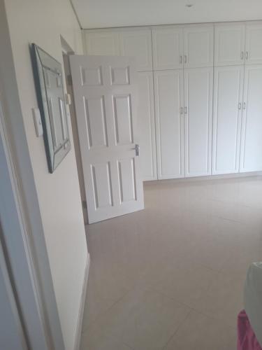 a bathroom with white cabinets and a door at 3/45 Oxley Road in Port Edward