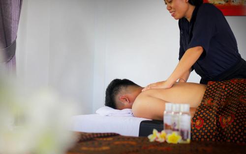 a woman is giving a man a massage at Rostika Hotel Sekumpul in Buleleng