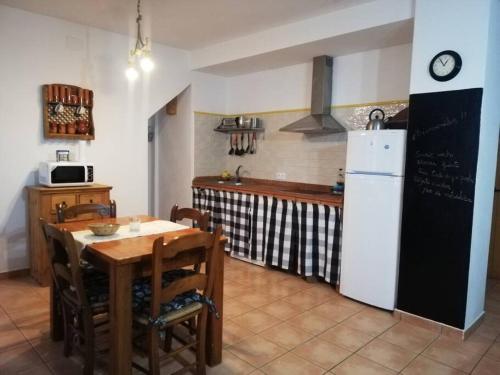 a kitchen with a table and a white refrigerator at Casa rural Alicia in Cortegana