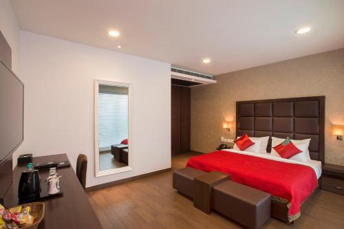 Jasmine Boutique Hotel Jasola في نيودلهي: غرفة نوم بسرير احمر مع بطانية حمراء