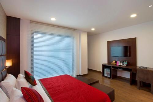 a bedroom with a bed and a large window with a television at Jasmine Boutique Hotel Jasola in New Delhi