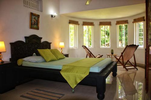 um quarto com uma cama com cadeiras e janelas em Silvawood Banglow em Rangala
