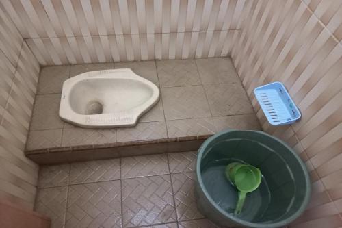 La salle de bains est pourvue d'un urinoir et d'un bol vert. dans l'établissement SPOT ON 93557 Juan Kostel 2, à Purwokerto