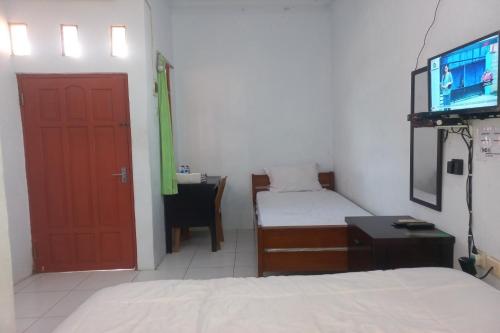 Habitación con puerta roja, cama y escritorio. en SPOT ON 93557 Juan Kostel 2, en Purwokerto
