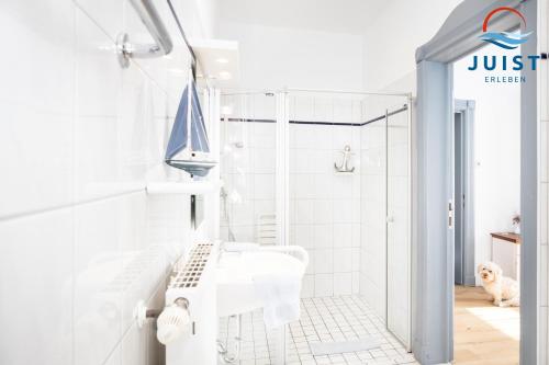 uma casa de banho branca com um chuveiro e um lavatório. em Pension Marie Luise 252 - Zimmer Venusmuschel em Juist