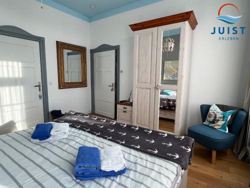 ein Schlafzimmer mit einem Bett und einem blauen Stuhl in der Unterkunft Pension Marie Luise 252 - Zimmer Venusmuschel in Juist