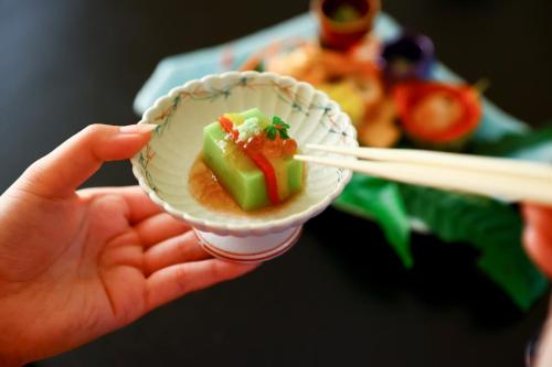 a person holding a cup of food with a chopstick at 別所温泉 七草の湯 in Ueda