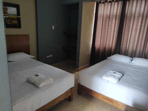 two beds in a room with two towels on them at Hostal Aventura Total Perú_lunahuana in Lunahuaná